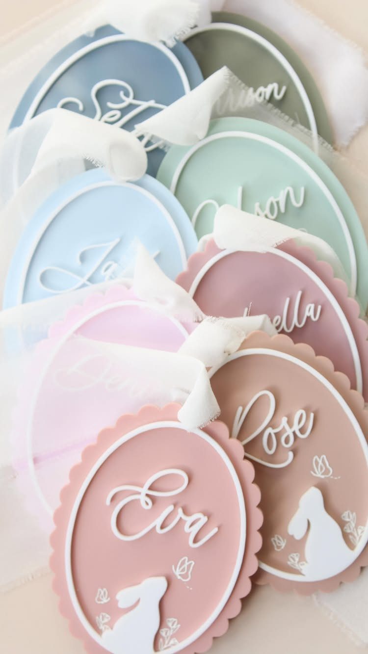 Pastel egg-shaped personalized name tags with bunny silhouettes and white ribbons.