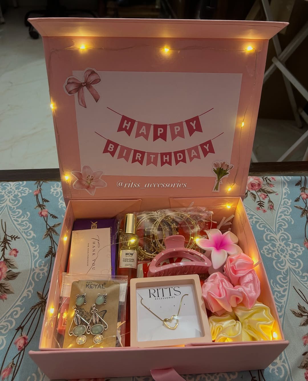 8 Small Gift for Mom Ideas, From Bath Soaks to Baskets 8 Pink gift box filled with jewelry, perfume, and hair accessories with fairy lights.