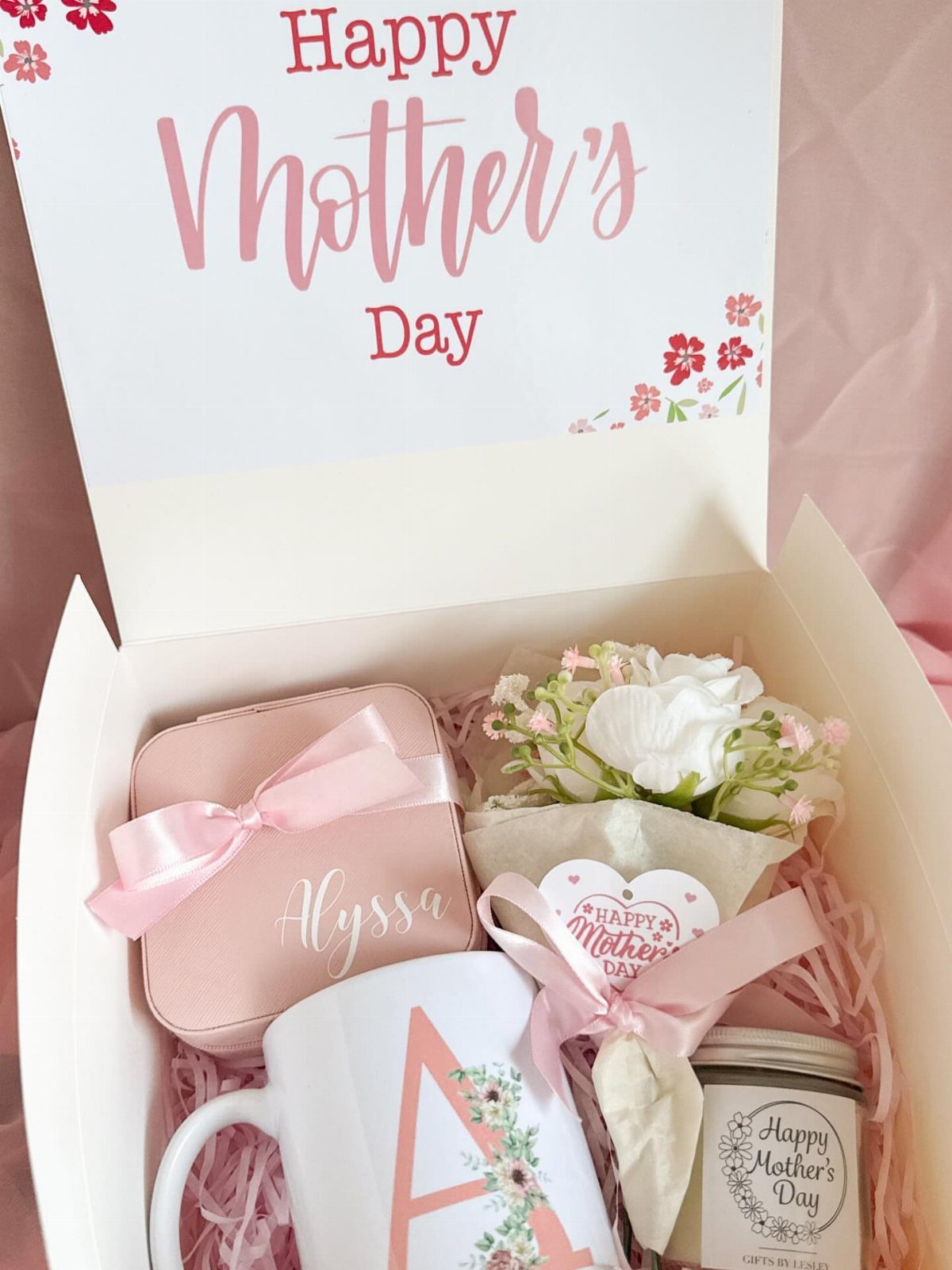 8 Small Gift for Mom Ideas, From Bath Soaks to Baskets 5 Gift box for Mother's Day with personalized mug, tin, candle, and white flowers.