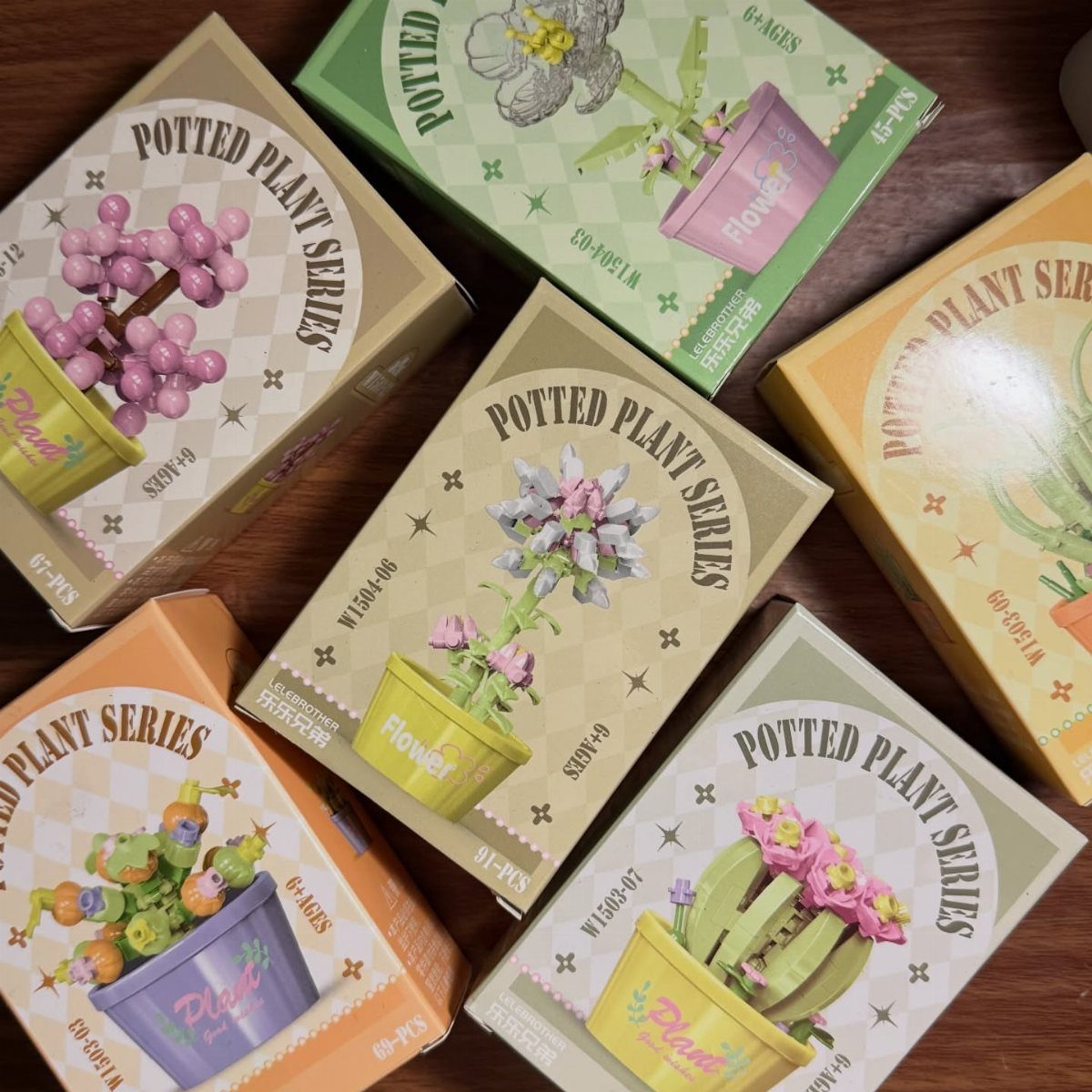 14 Small Unisex Gifts for Friends, Coworkers and Family 7 Potted Plant Series building block boxes arranged on a dark wooden table.