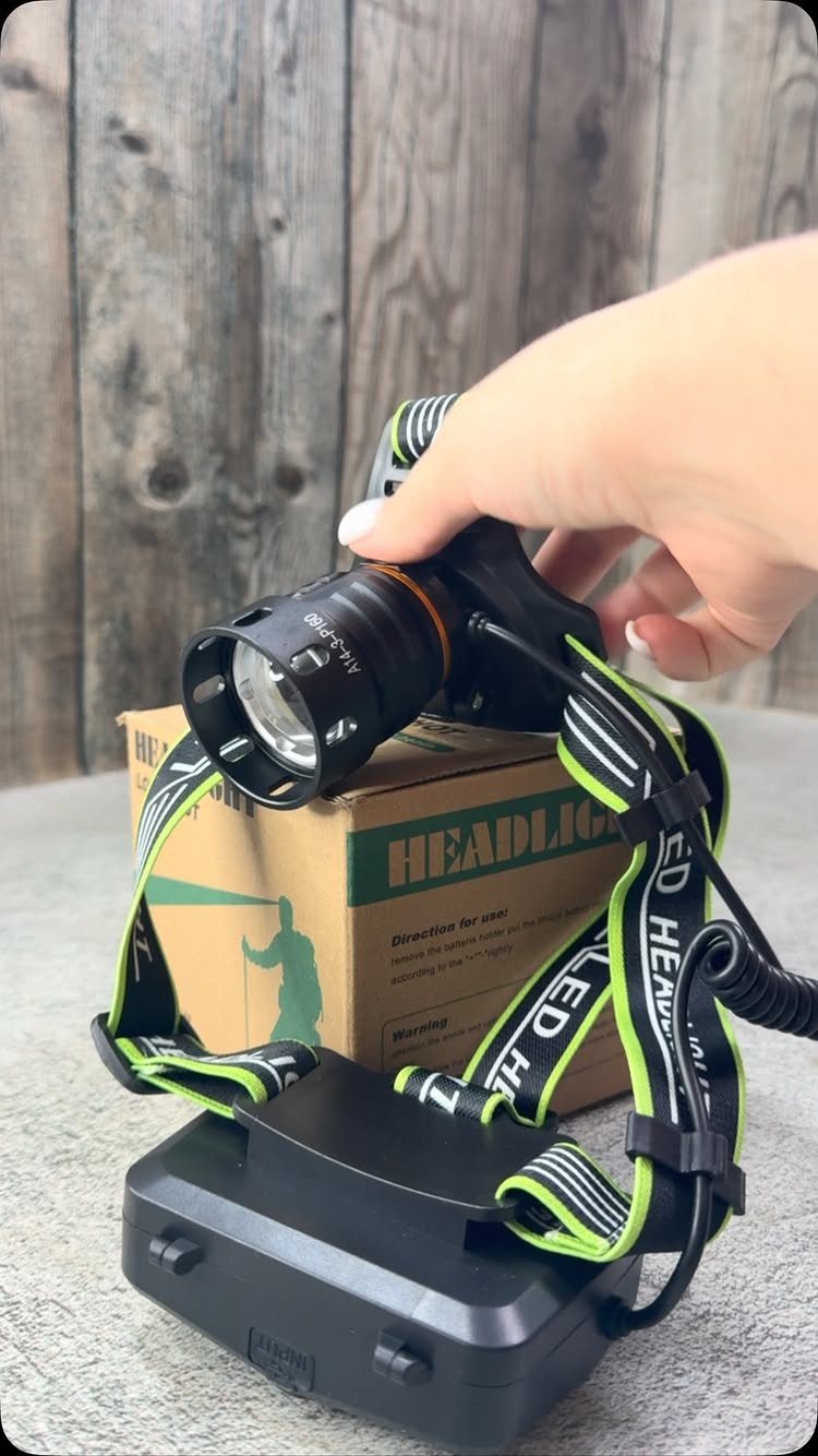 14 Small Unisex Gifts for Friends, Coworkers and Family 11 Black headlamp with green straps held over its cardboard packaging box.