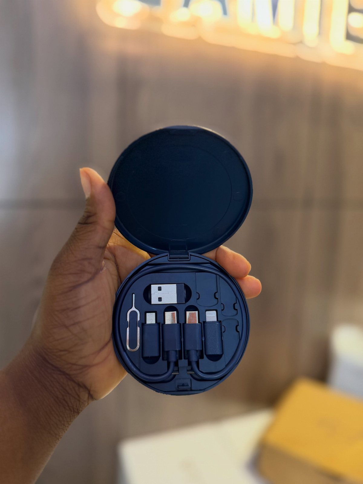 14 Small Unisex Gifts for Friends, Coworkers and Family 12 Navy blue circular cable organizer case held in a hand with charging adapters.