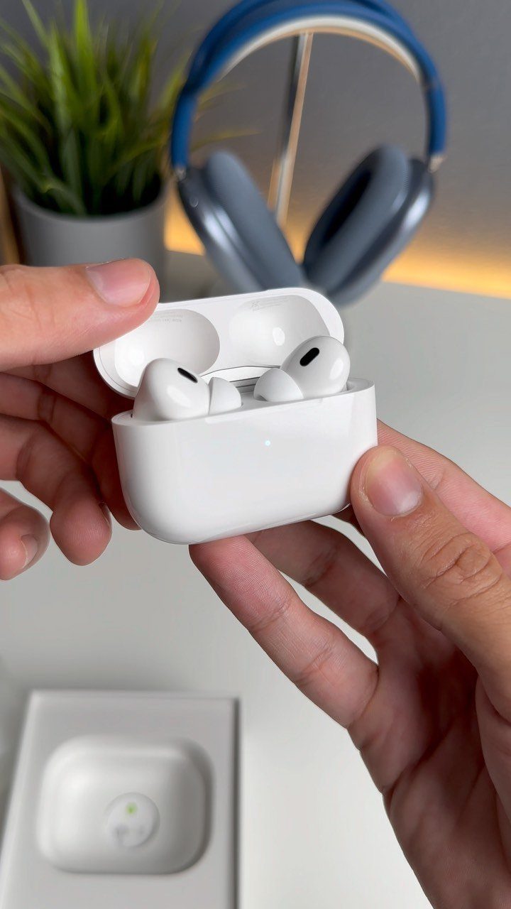 14 Small Unisex Gifts for Friends, Coworkers and Family 4 Wireless earbuds in a white charging case held by two hands on a desk