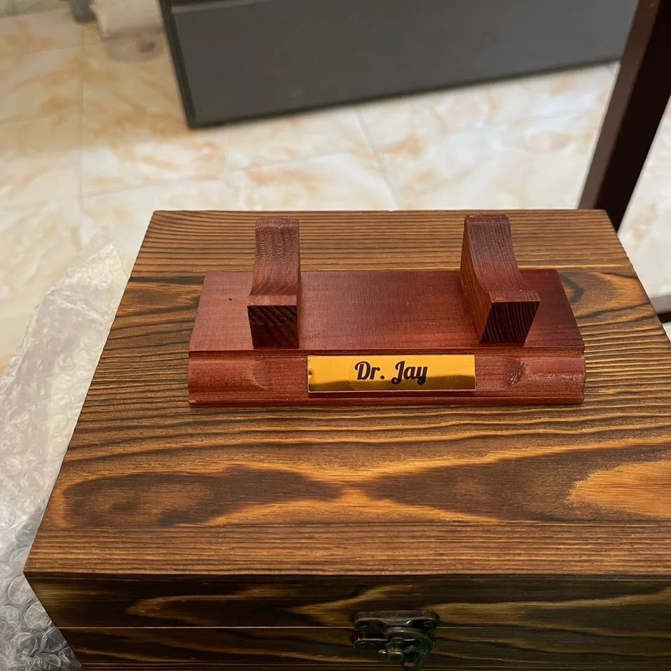 10 Special Gifts for Dad: Personalized Picks He'll Keep 9 Wooden cigar rest with gold nameplate sitting on a dark wooden box.