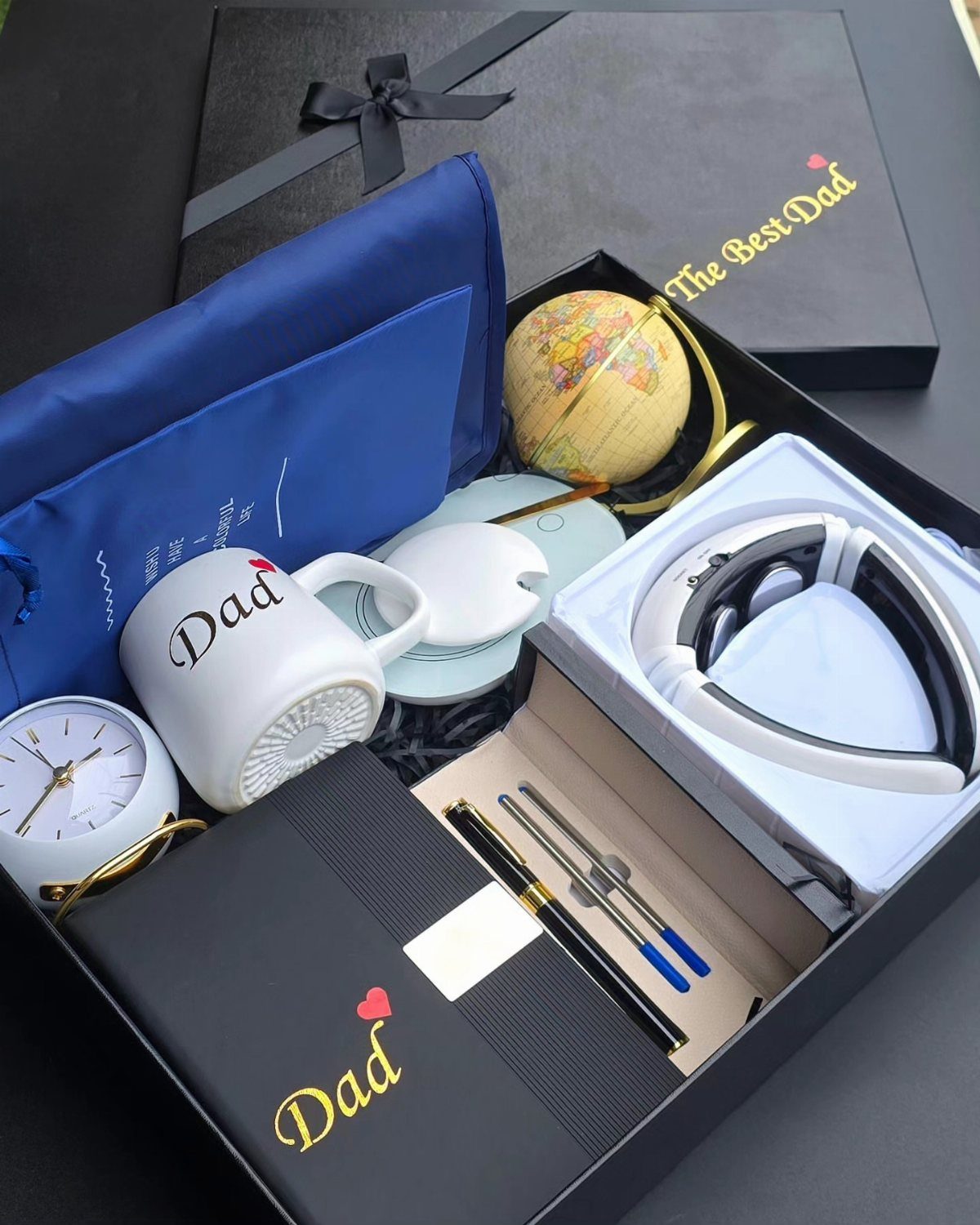 11 Step Father Gifts: From a Pocket Knife to a Photo Plaque 5 Black gift box for Dad containing a mug, globe, clock, and headphones.