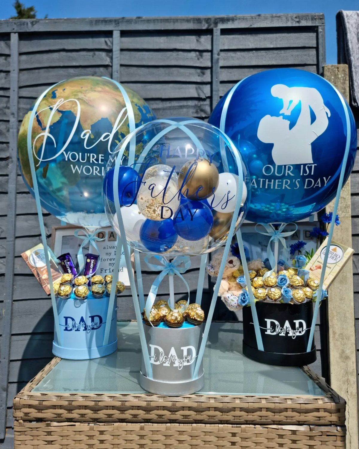11 Step Father Gifts: From a Pocket Knife to a Photo Plaque 10 Three Father's Day gift balloon arrangements with chocolates and Dad labels on a table.