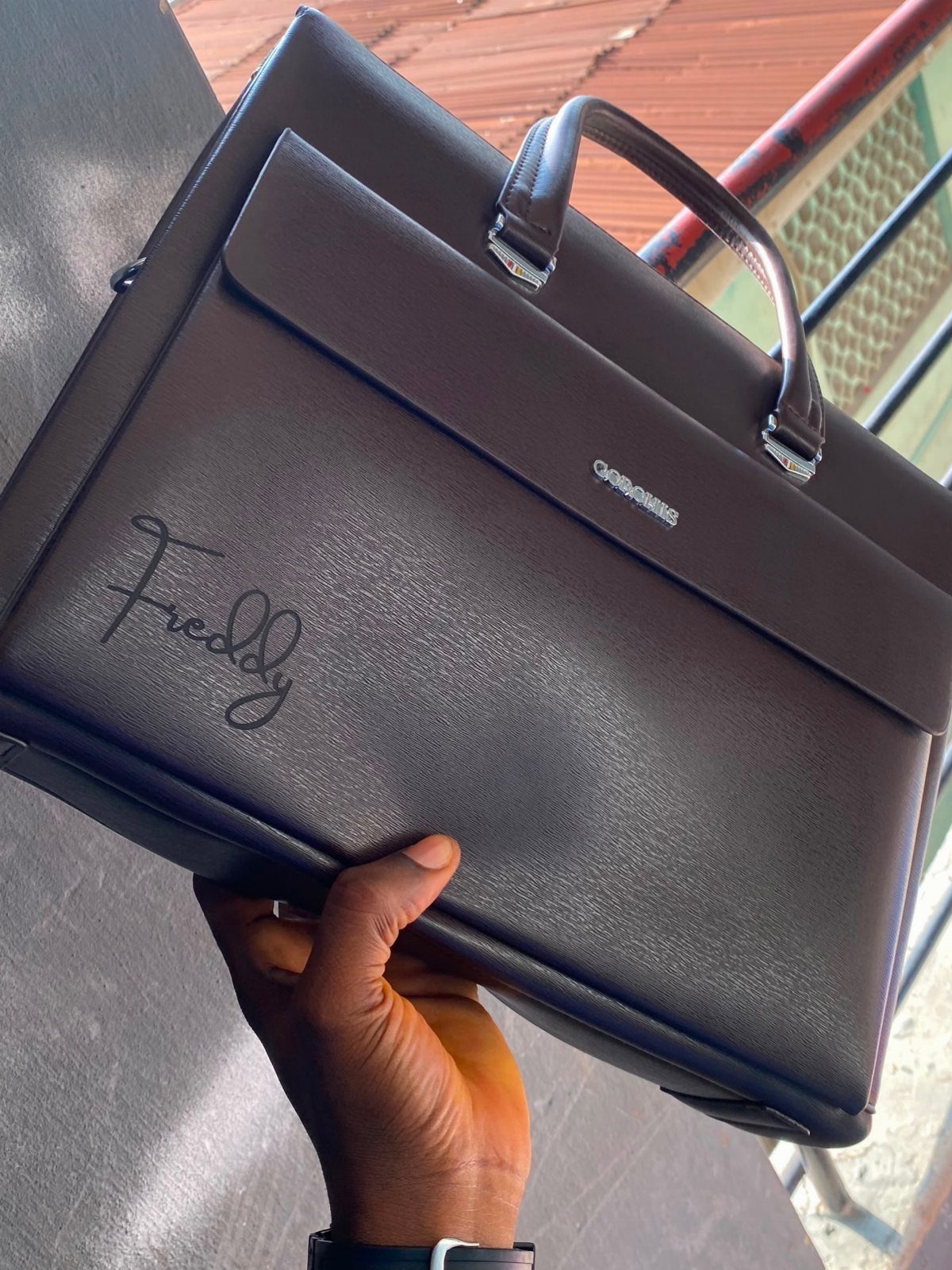 Dark brown leather messenger bag with the name Freddy written in cursive script.