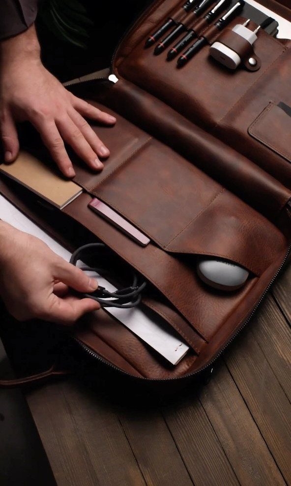 Brown leather portfolio case with pens and mouse on a wooden table