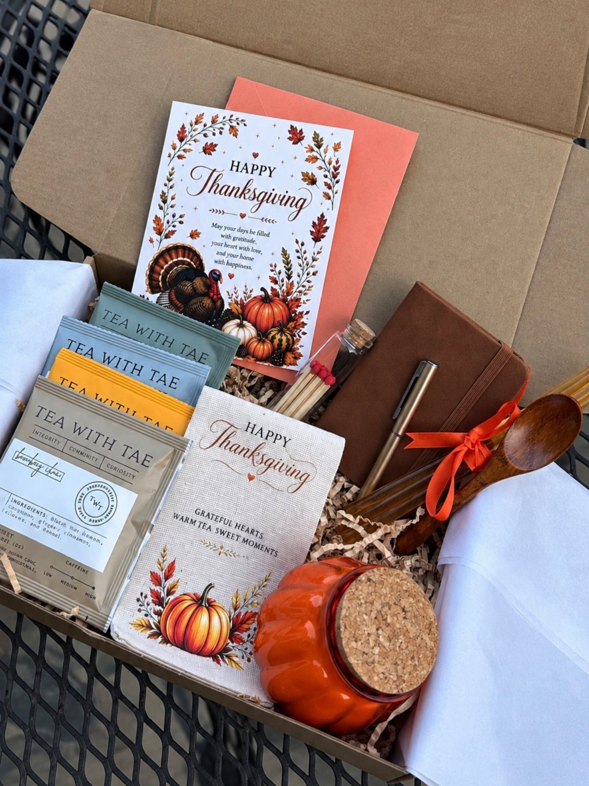 8 Thanksgiving Gift Box Ideas for Hosts and Friends 7 Thanksgiving gift box containing autumn stationery, tea, a pumpkin jar, and a wooden spoon.