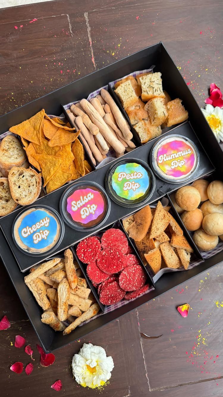 8 Thanksgiving Gift Box Ideas for Hosts and Friends 1 Gourmet snack basket with assorted chips, breads, crackers, and four colorful dip containers.