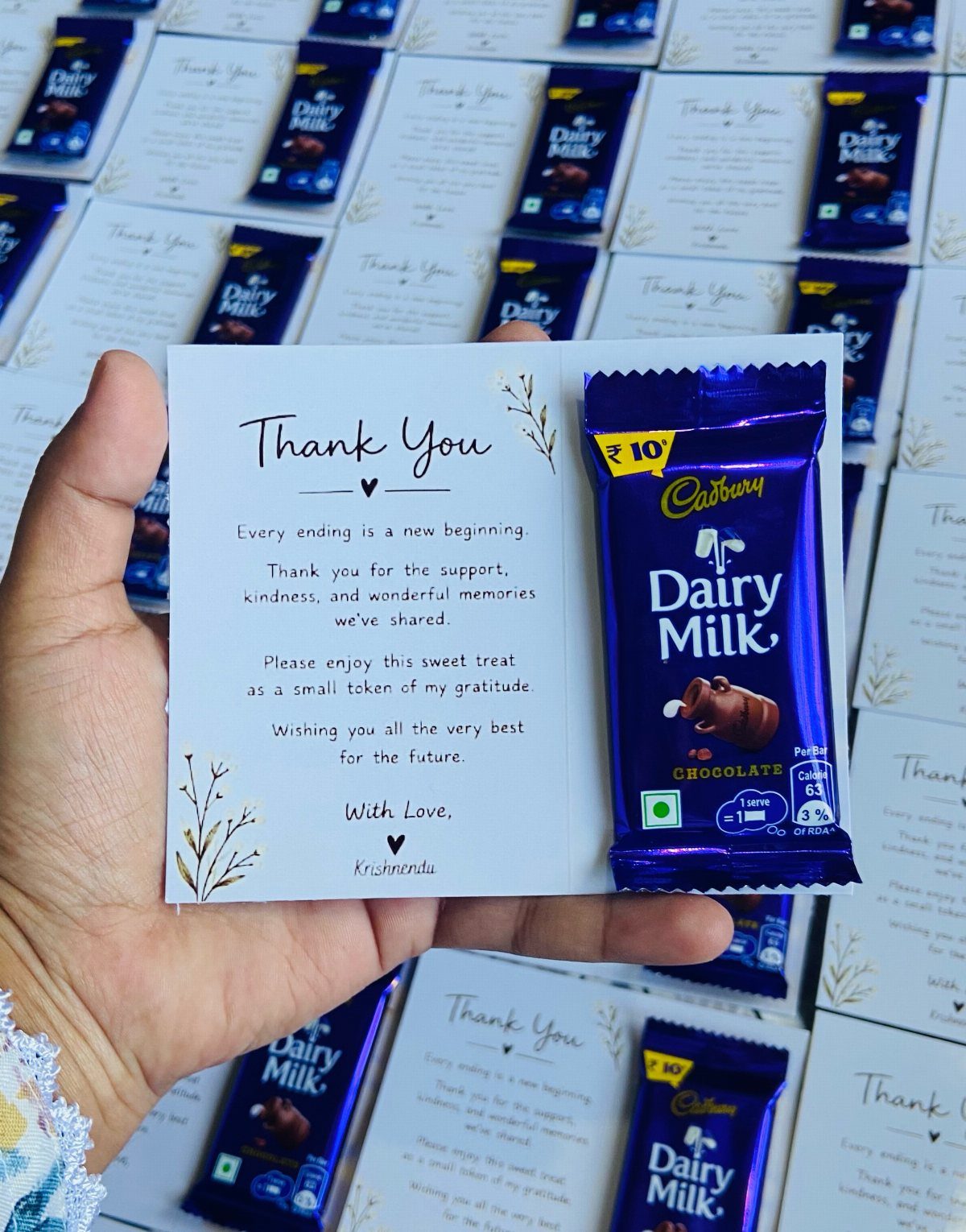 12 Thanksgiving Gifts for Coworkers They'll Actually Use 3 Hand holding a thank you note paired with a small chocolate bar.