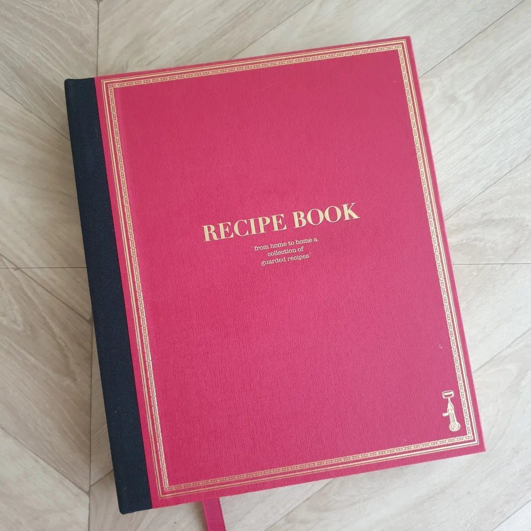 11 Thanksgiving Gifts for Family, From Candles to Cozy Throws 3 Red hardcover recipe book with gold lettering on a light wooden floor