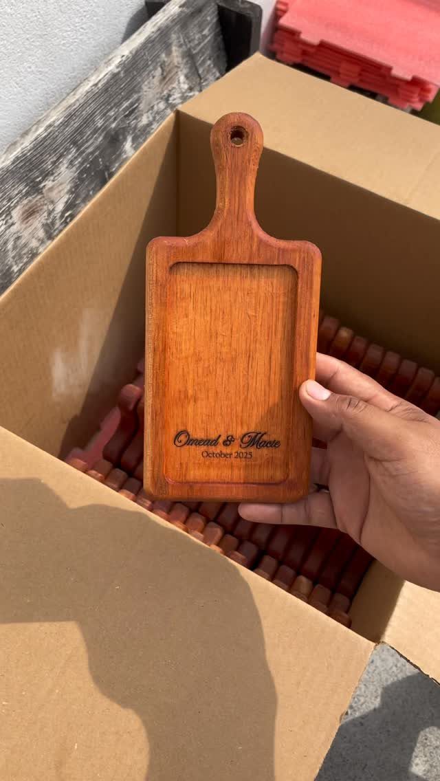 11 Thanksgiving Gifts for Family, From Candles to Cozy Throws 9 Wooden serving board with engraved names held inside a brown cardboard shipping box