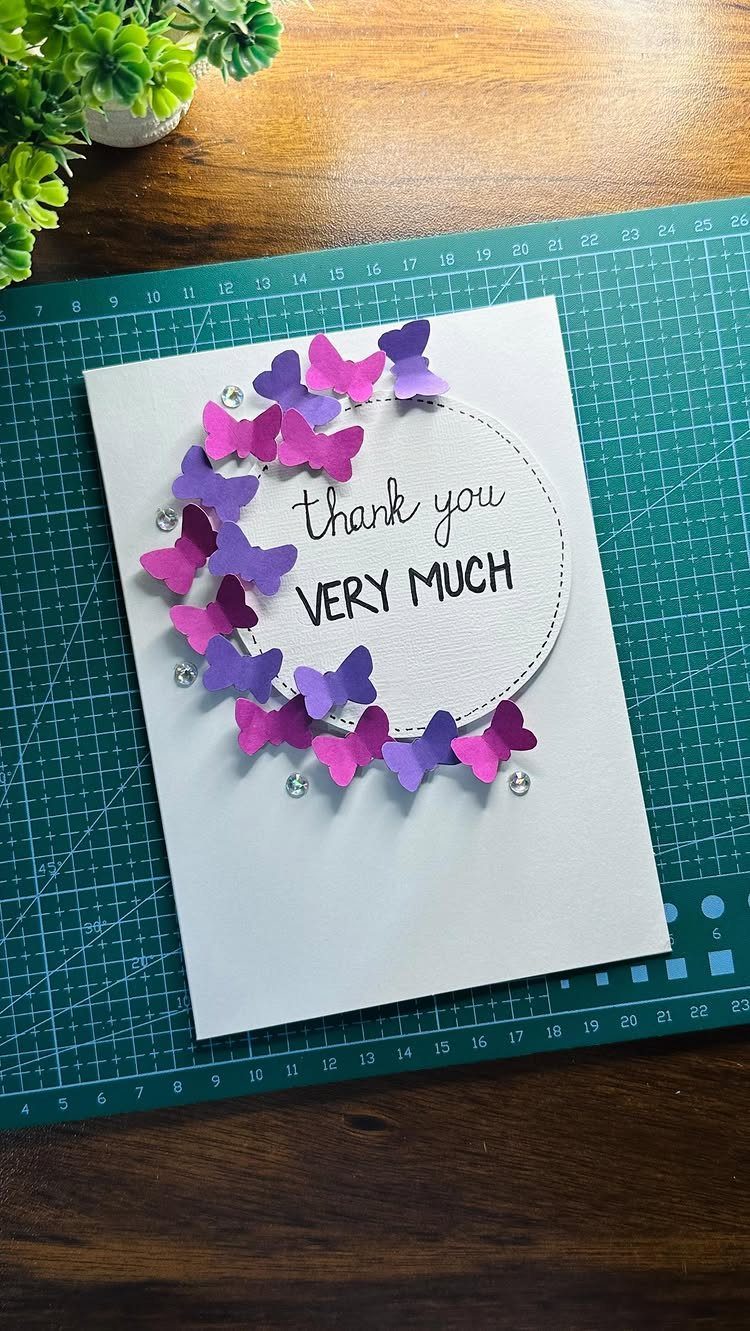 11 Thanksgiving Gifts for Family, From Candles to Cozy Throws 10 Handmade thank you card with purple butterflies on a green cutting mat