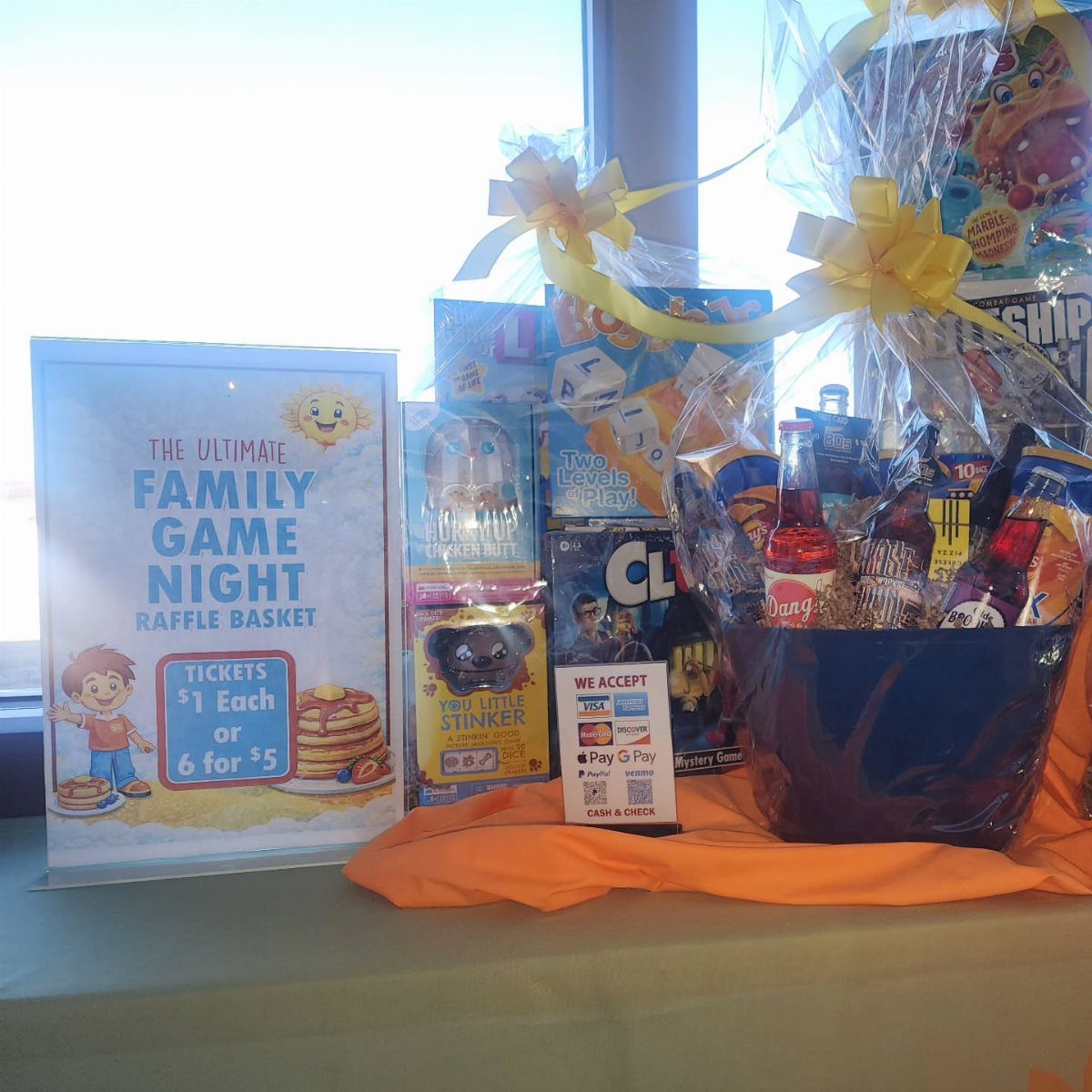 Blue gift basket filled with board games and snacks for a game night raffle.