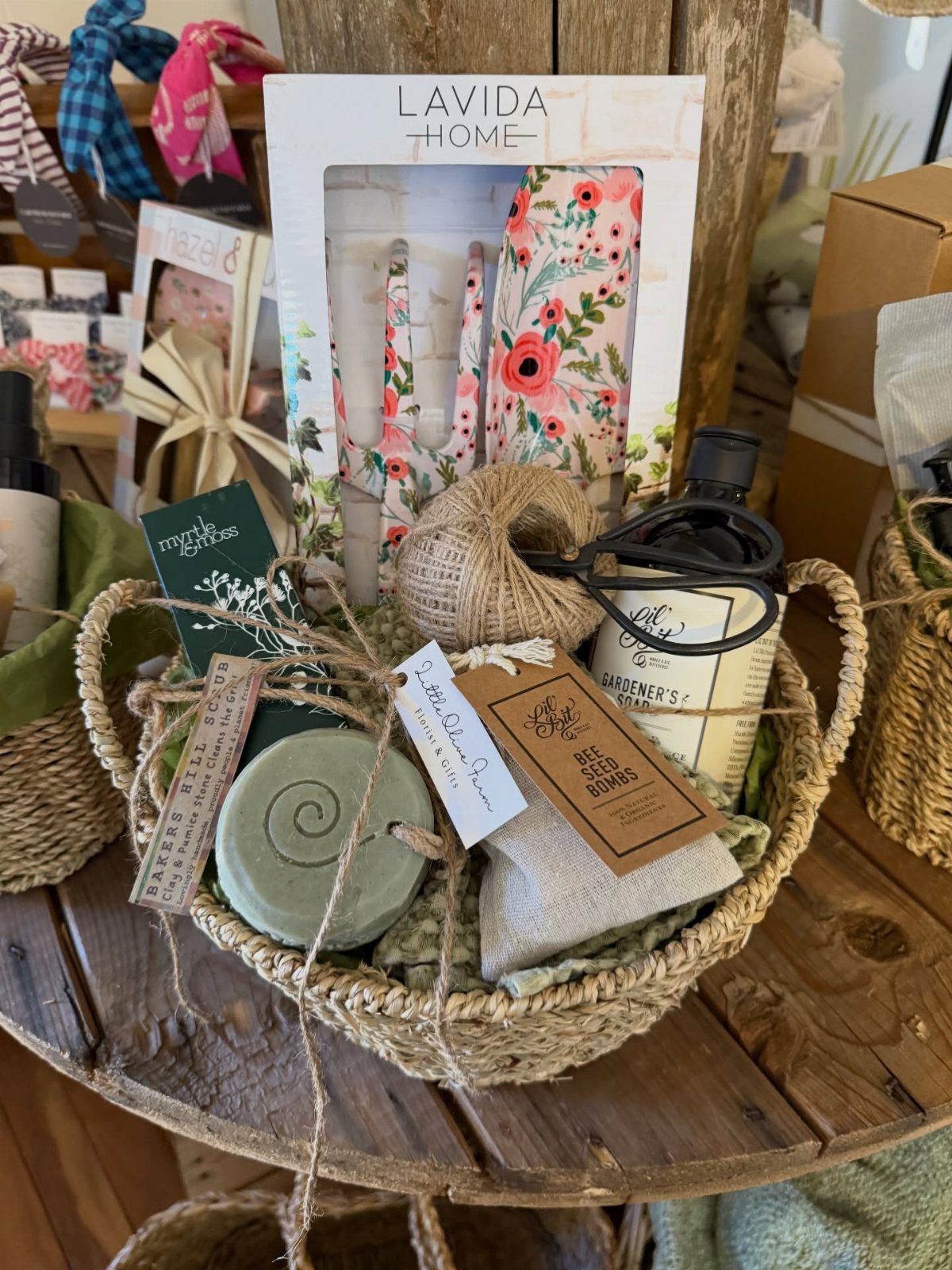 Woven gift basket containing gardener's soap, seed bombs, and floral home goods.
