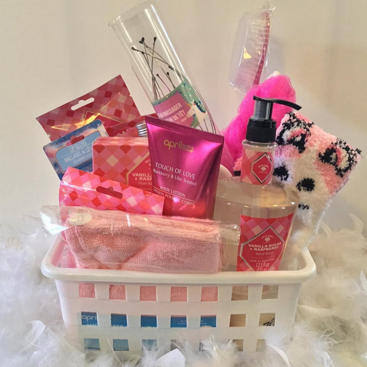 White basket filled with pink lotions, sponges, and beauty products for a spa gift.