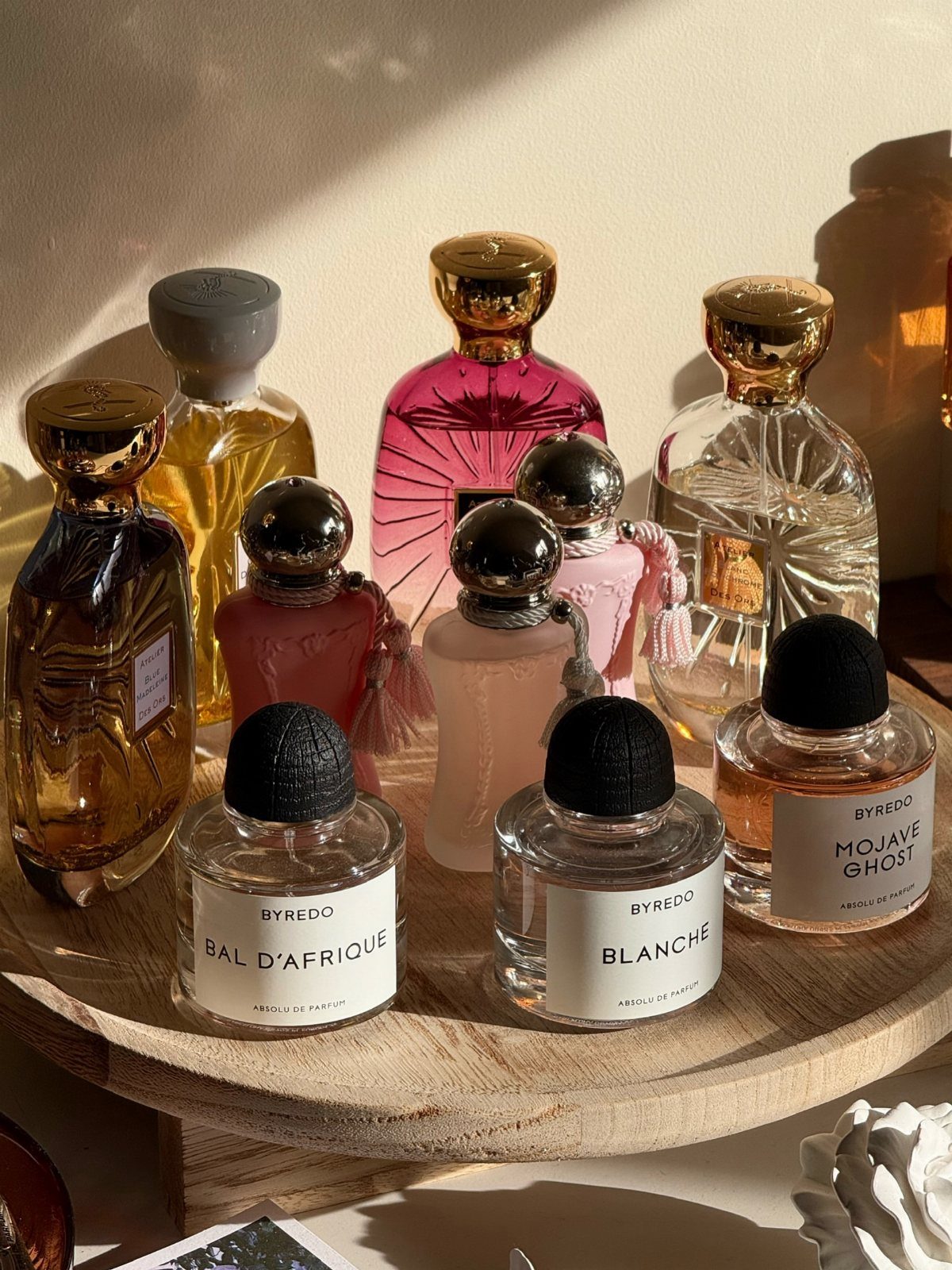 29 Trendy Gift Ideas for Her: The 2026 Gift Guide 4 Various perfume bottles, including Byredo fragrances, arranged on a round wooden tray.