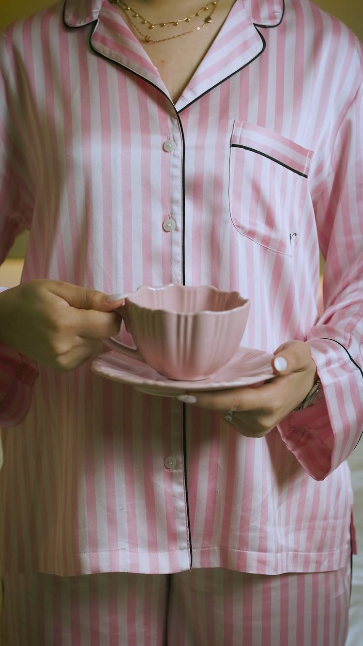 29 Trendy Gift Ideas for Her: The 2026 Gift Guide 9 Person in pink striped satin pajamas holding a matching pink teacup and saucer.