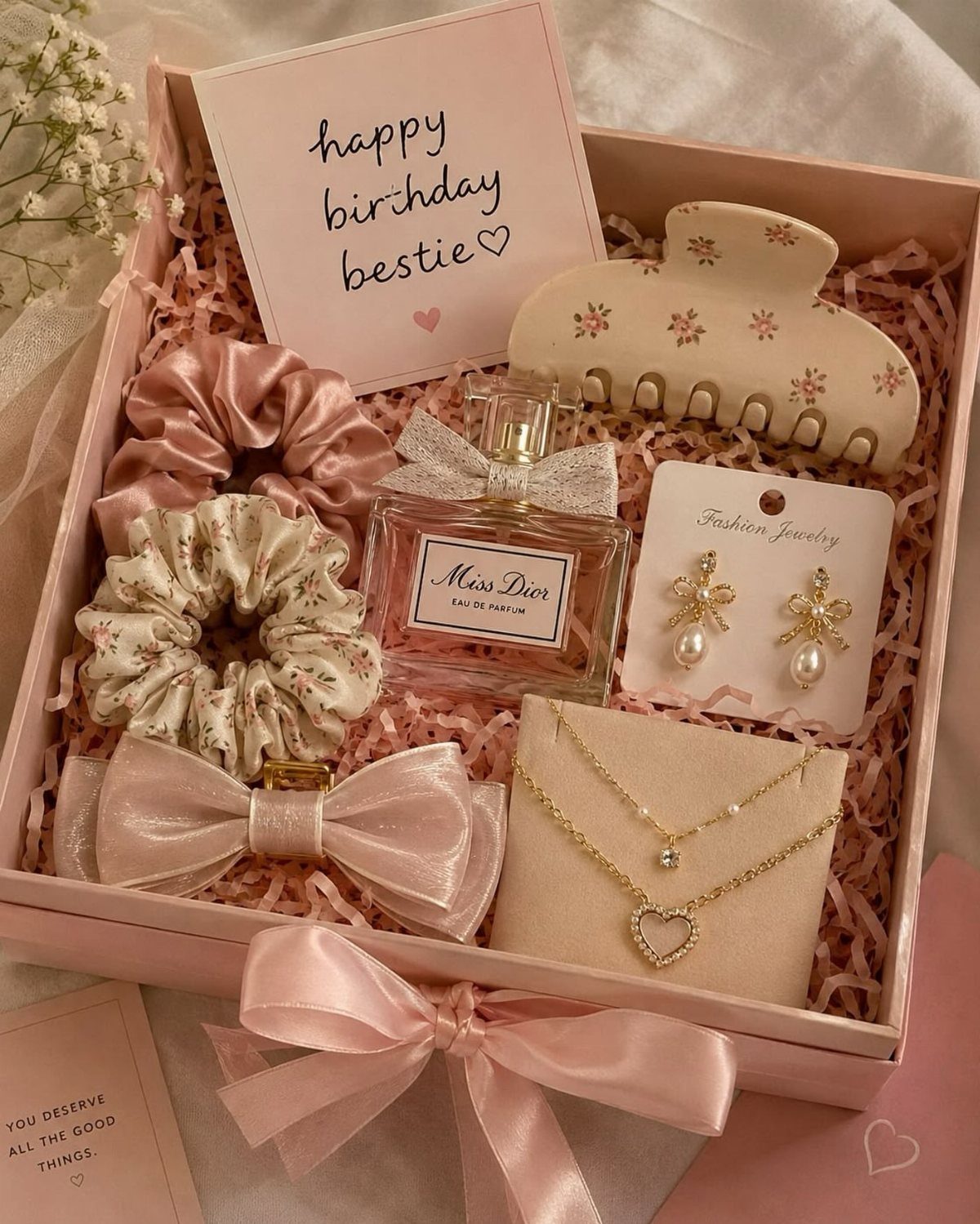 29 Trendy Gift Ideas for Her: The 2026 Gift Guide 13 Pink gift box containing Dior perfume, gold jewelry, scrunchies, and a birthday card.