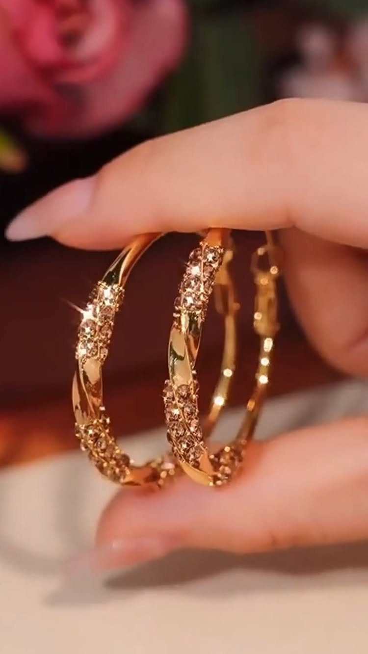 29 Trendy Gift Ideas for Her: The 2026 Gift Guide 7 Gold hoop earrings with twisted crystal details held between two fingers.