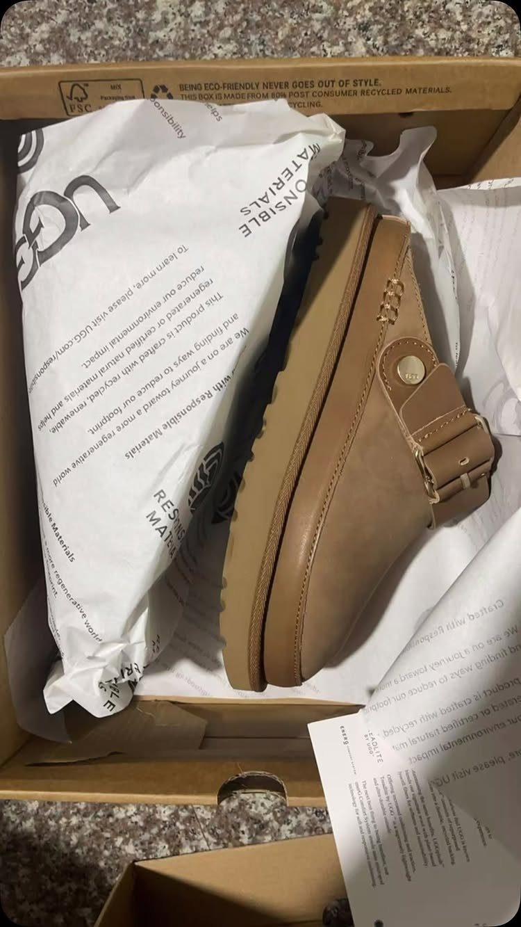29 Trendy Gift Ideas for Her: The 2026 Gift Guide 24 Tan UGG boot with buckle strap inside a cardboard shoebox with tissue paper.