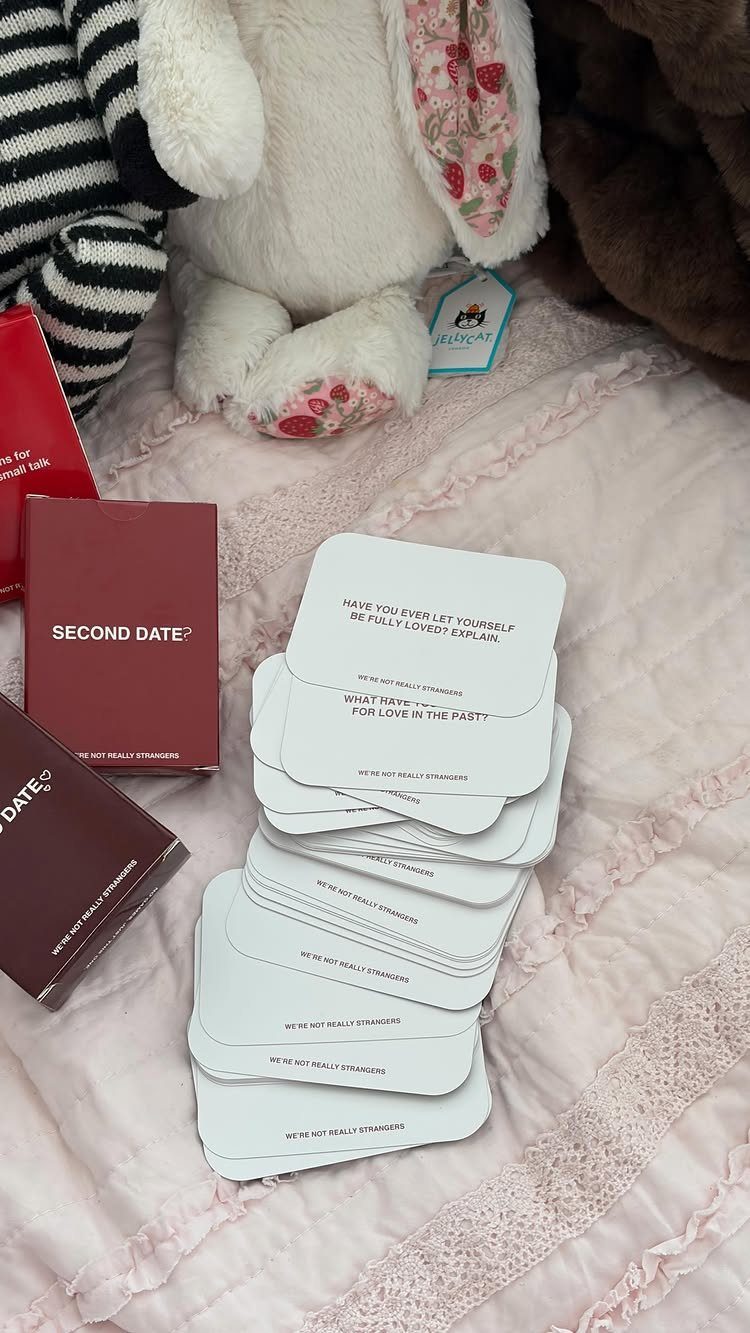 29 Trendy Gift Ideas for Her: The 2026 Gift Guide 11 Stack of white conversation cards and red boxes next to a plush bunny.