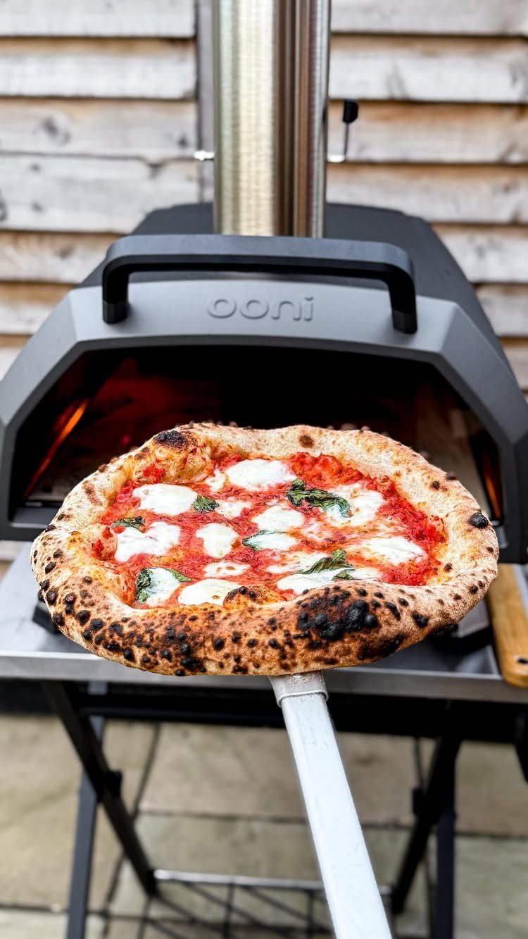 12 Useful Gifts for Dad: Practical Picks He'll Actually Use 7 Margherita pizza being removed from a black outdoor pizza oven with a metal peel