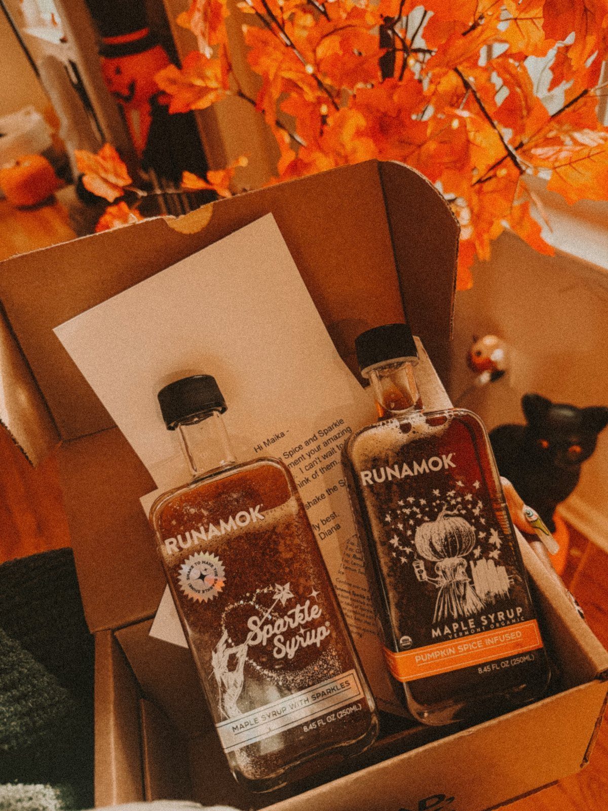 12 Useful Gifts for Dad: Practical Picks He'll Actually Use 6 Two bottles of Runamok maple syrup inside a cardboard shipping box with autumn leaves.