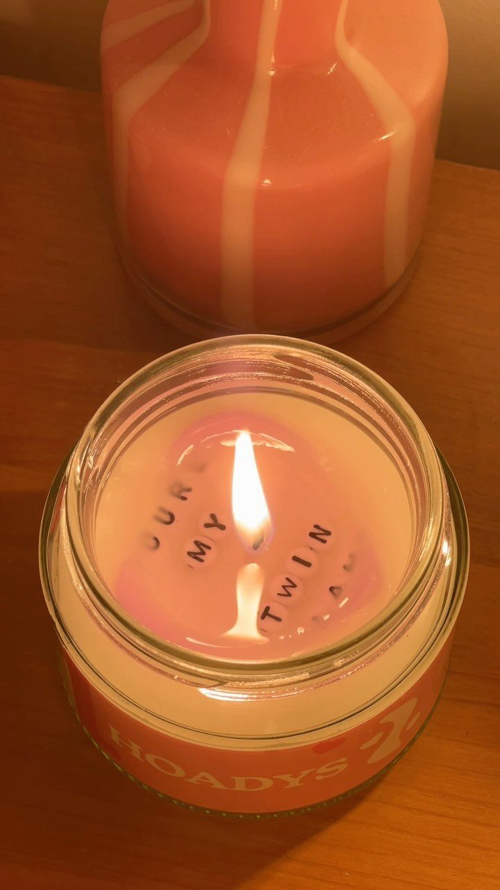 Lit pink candle in a glass jar with letters spelling YOUR MY TWIN