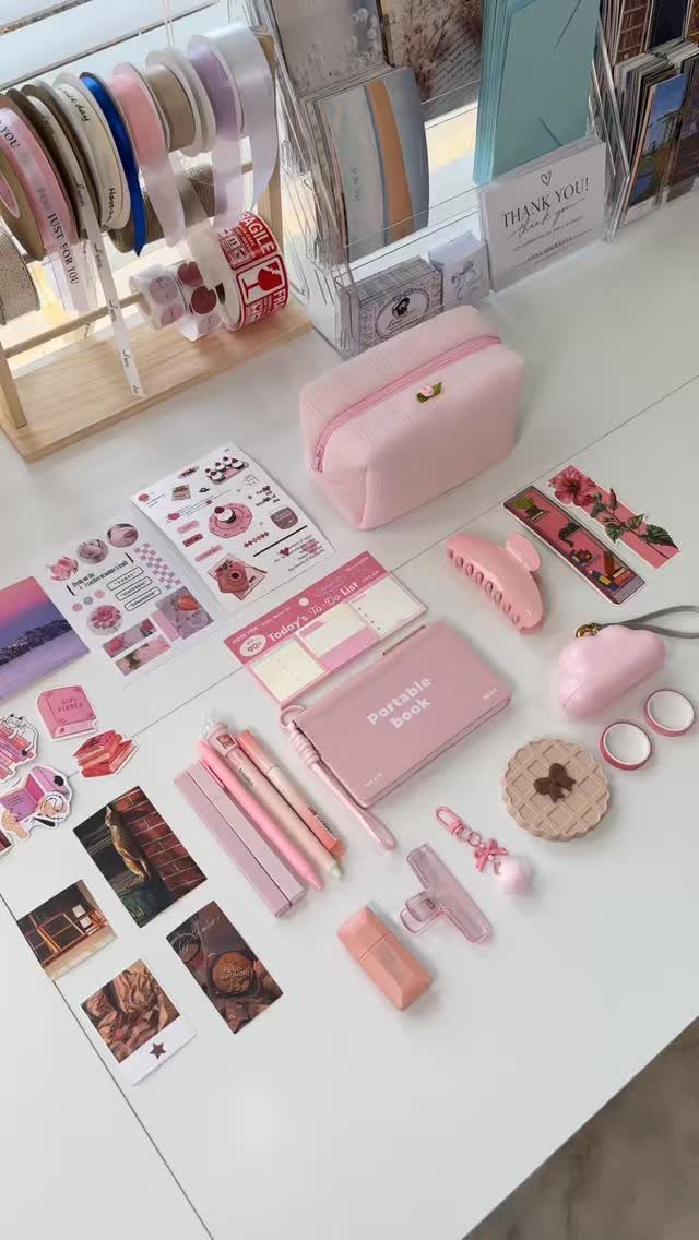 Pink stationery set with pens, stickers, and a pouch on a white desk