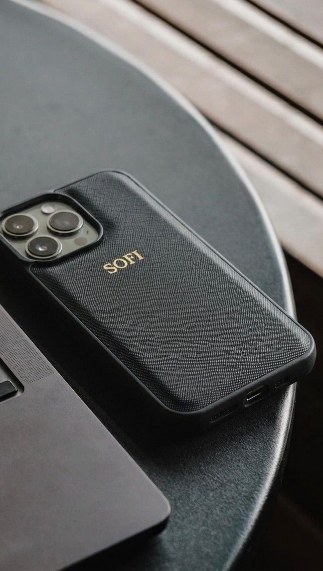 Black textured phone case with gold personalized name SOFI on a dark table