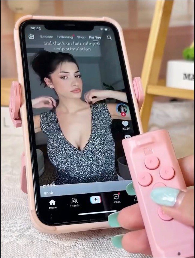 Pink smartphone tripod and remote shutter used to record a video on a phone