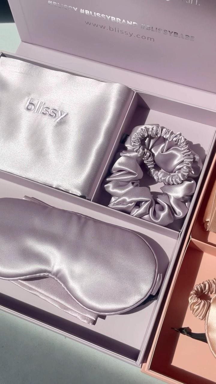 Satin sleep mask, scrunchie, and pillowcase inside a light purple gift box.