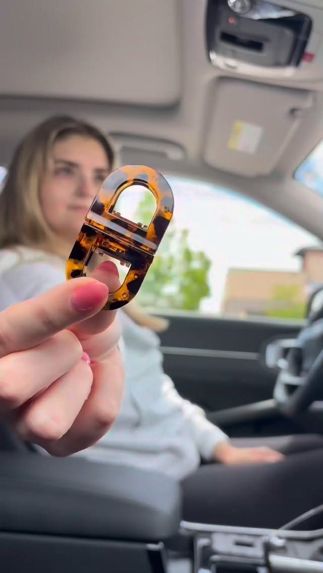 Tortoiseshell hair claw clip held up in front of a woman in a car