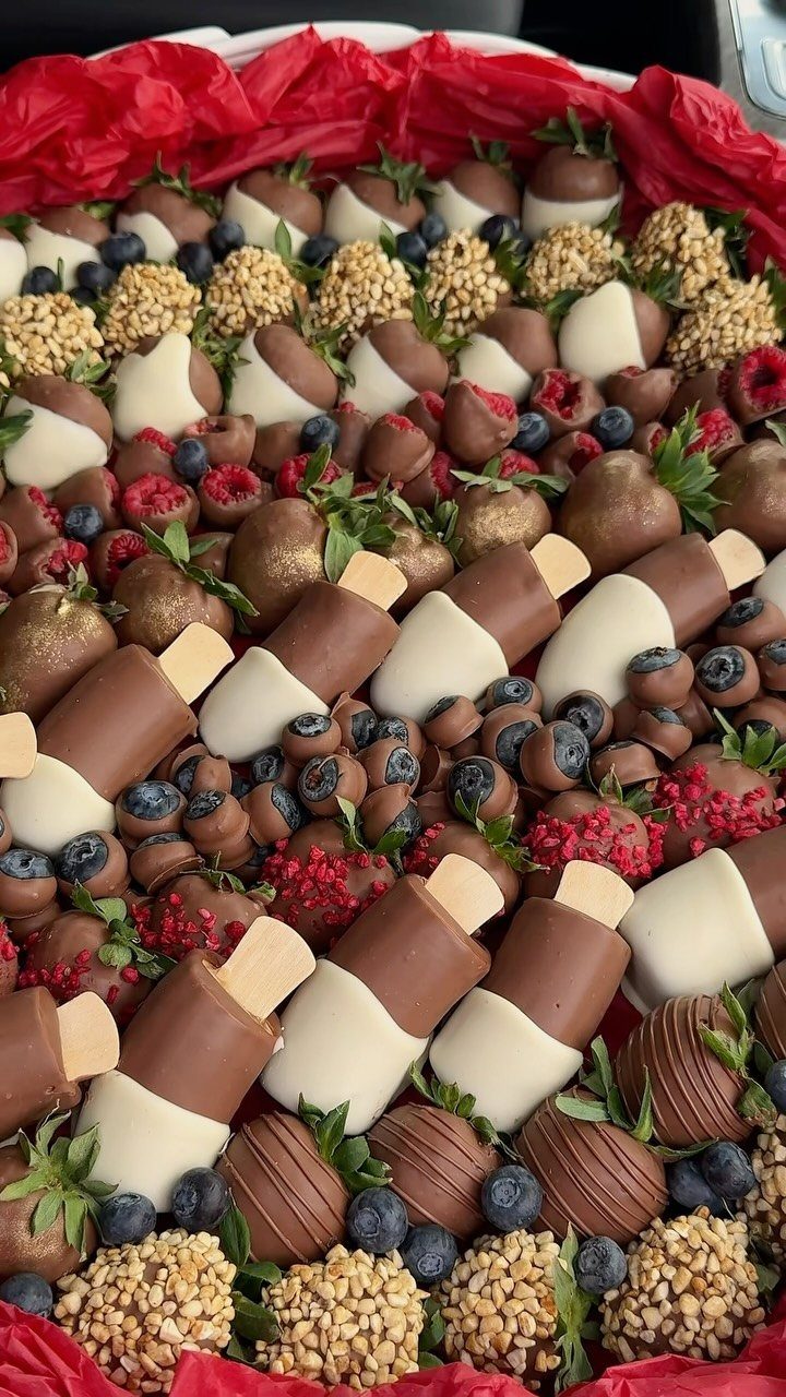 Chocolate covered strawberries and fresh berries arranged in a white gift basket