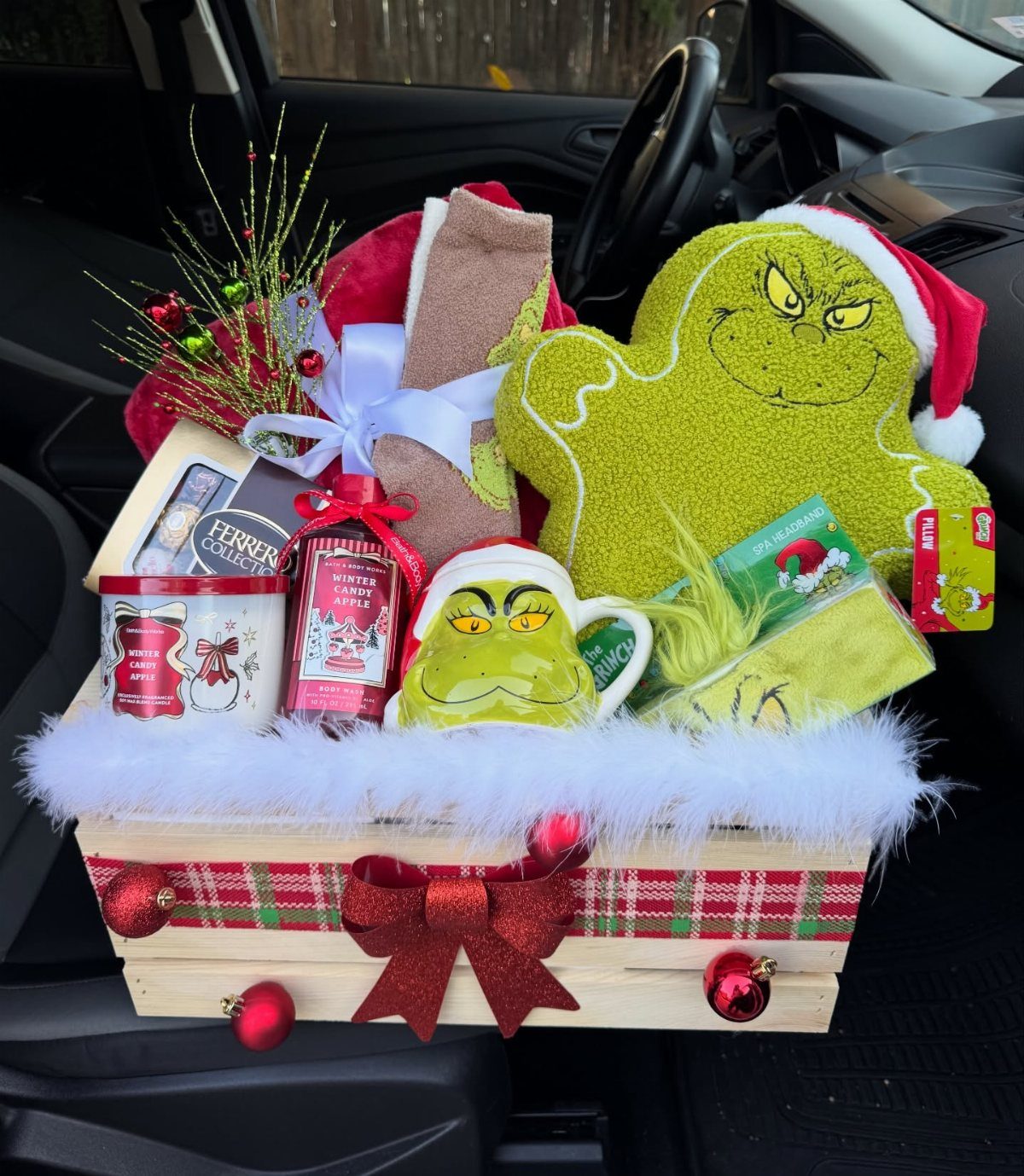 Grinch-themed Christmas gift basket in a wooden crate with plush and treats