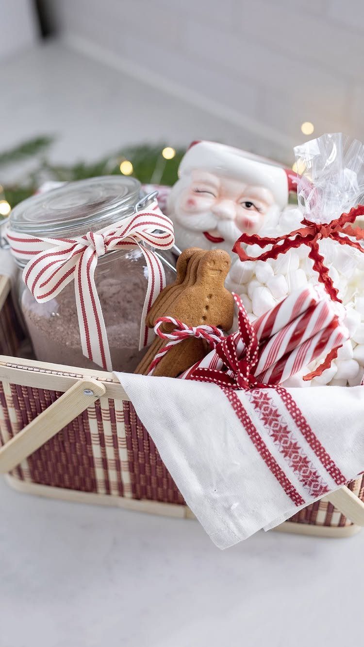 Christmas gift basket filled with cocoa, gingerbread, candy canes, and a Santa figurine.