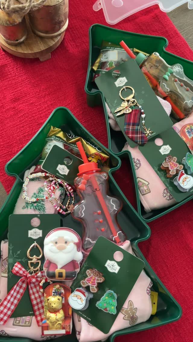 Two green tree-shaped gift baskets filled with Christmas themed treats and accessories.