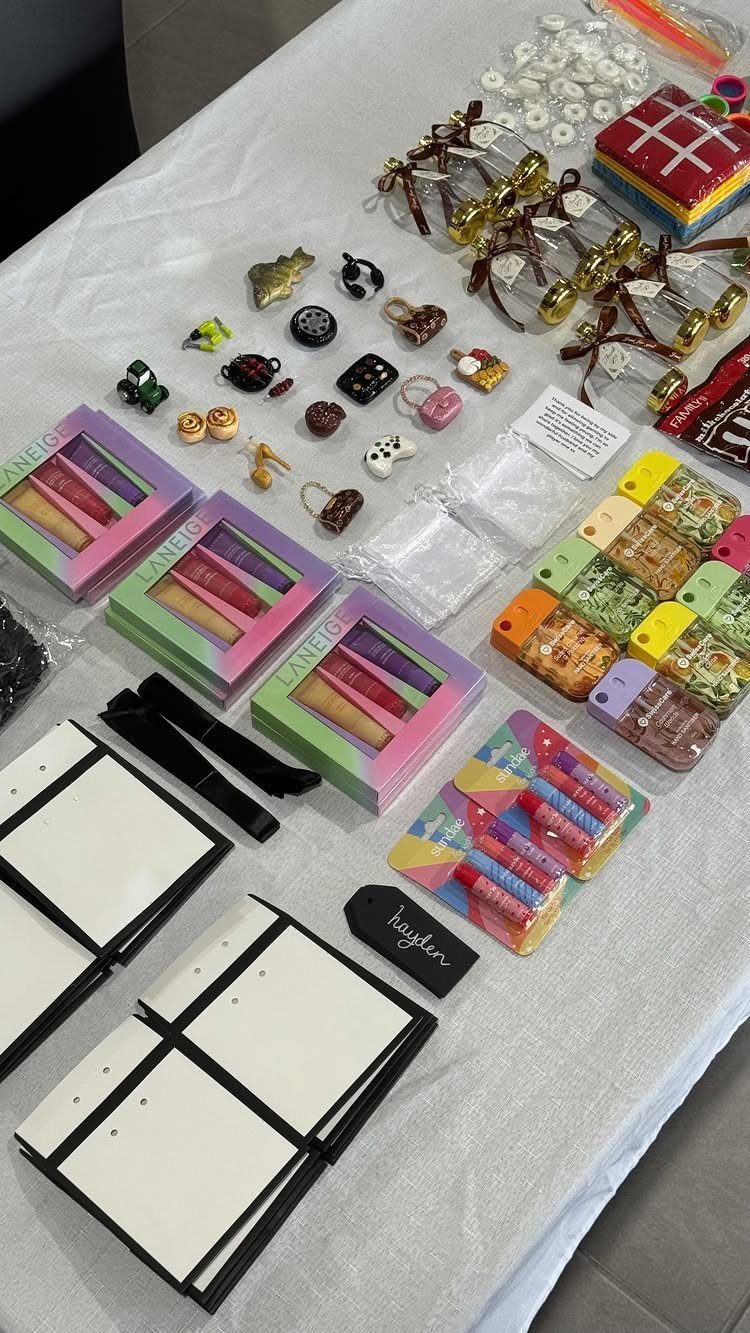 Assorted small gifts and beauty products arranged on a white tablecloth for party favors.