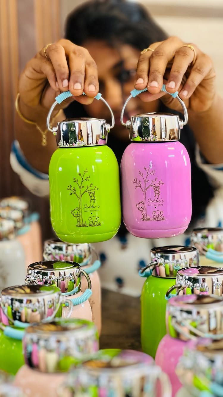 Two reusable water bottles in green and pink held by a person.