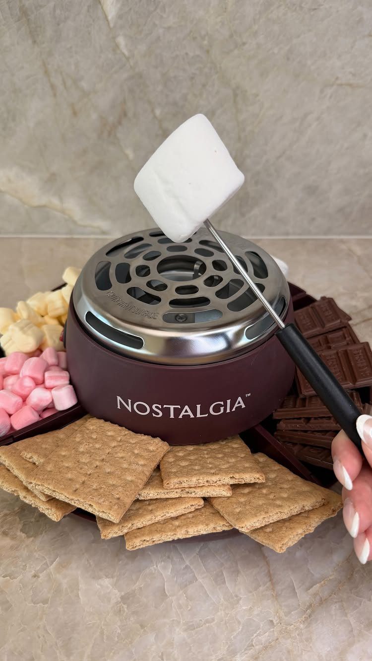 Electric s'mores maker with graham crackers, chocolate, and a roasting marshmallow.
