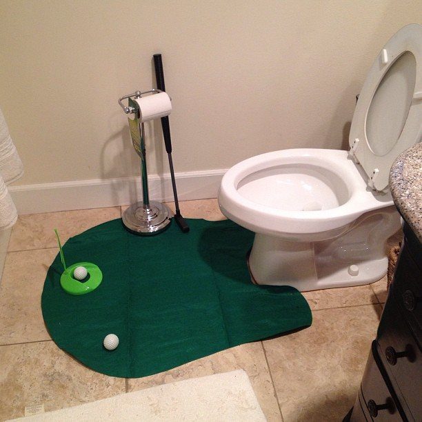 Mini golf putting mat and balls set up on a bathroom floor.